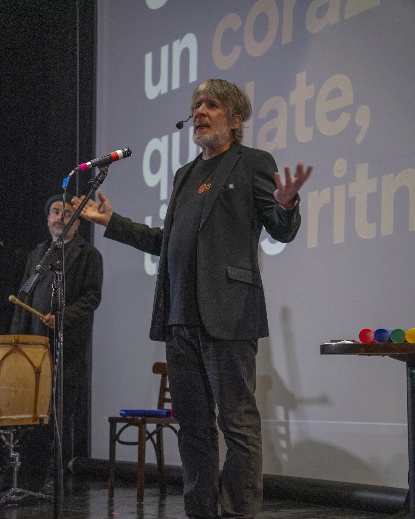 Marcos Ribas en el escenario, con micrófono de diadema y una mano abierta, durante una de sus conferencias.